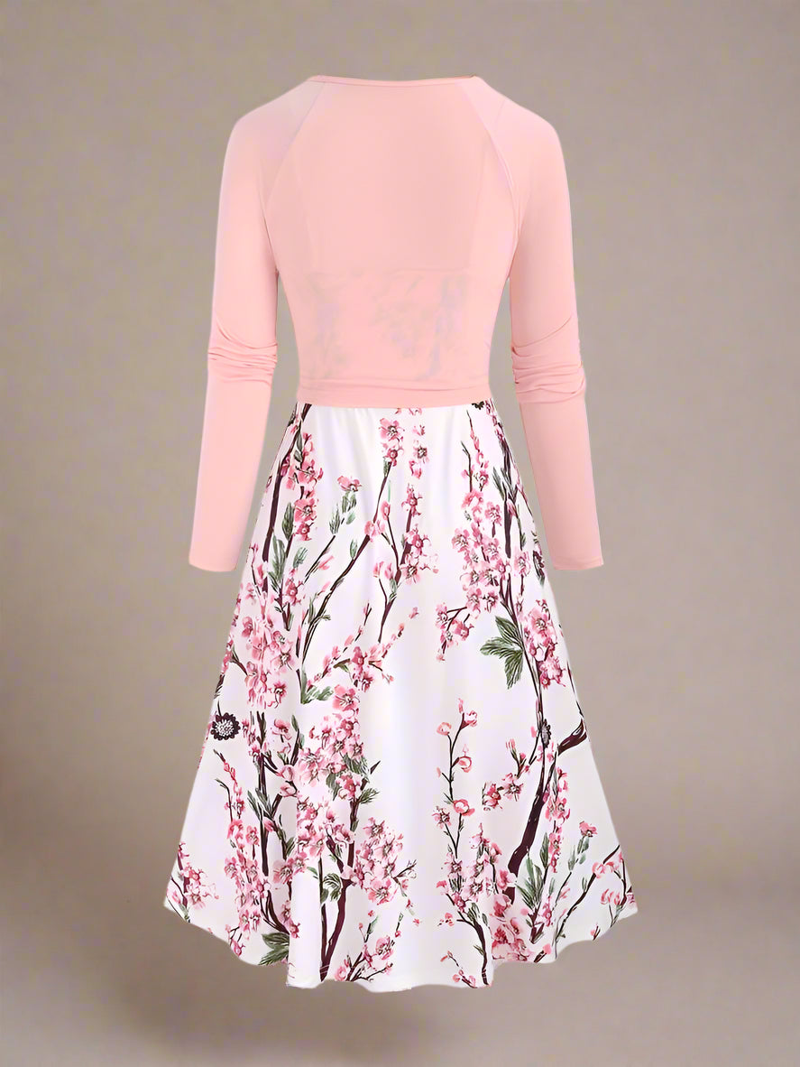 White sundress with detailed pink cherry blossom branches and subtle green foliage print, styled in a classic A-line silhouette with spaghetti straps and a flowy dress.