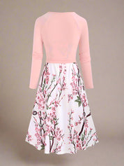 White sundress with detailed pink cherry blossom branches and subtle green foliage print, styled in a classic A-line silhouette with spaghetti straps and a flowy dress.