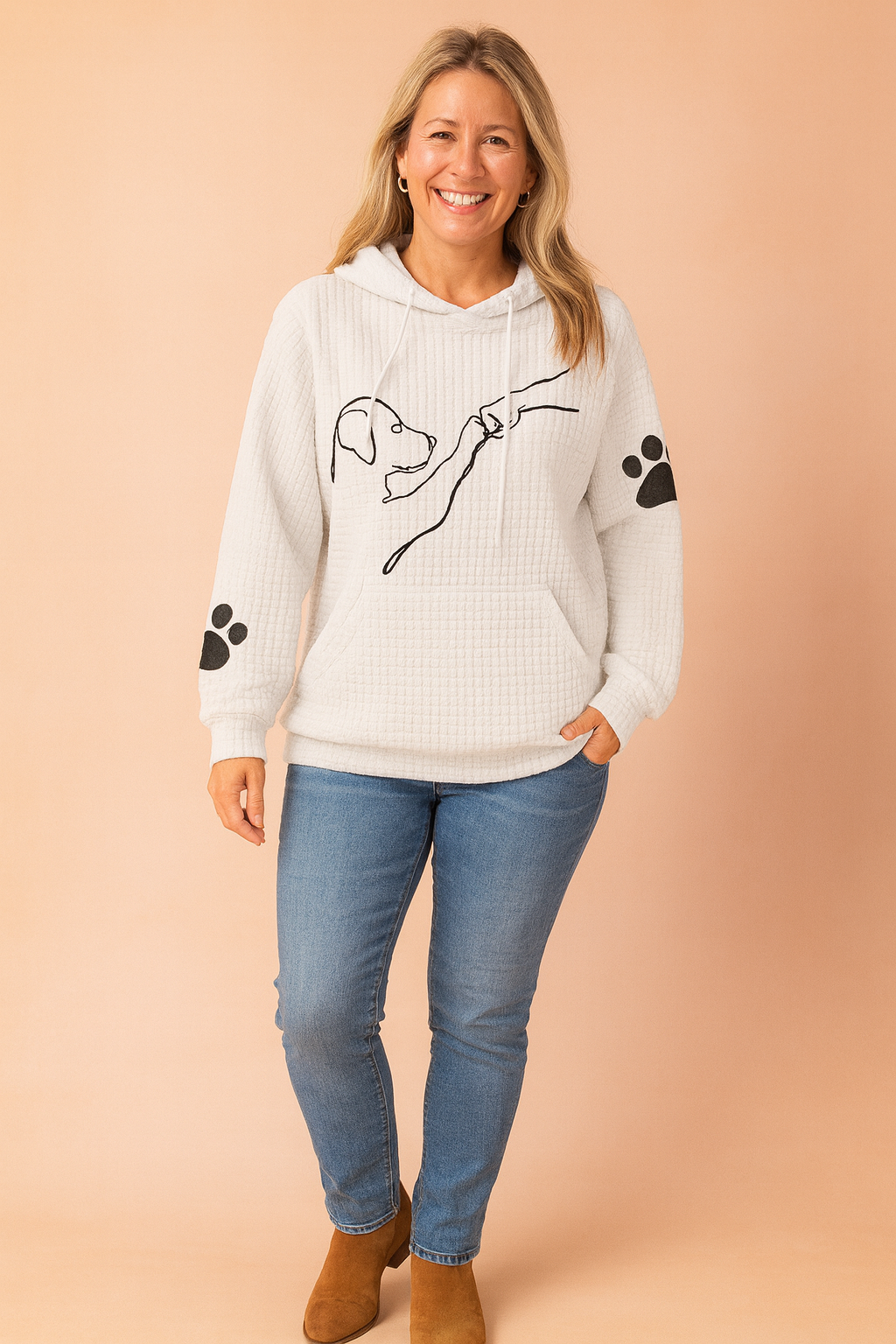 White waffle-textured hoodie with black minimalist dog illustration and paw print graphics on sleeves, styled with mid-rise skinny jeans and navy lace-up sneakers.