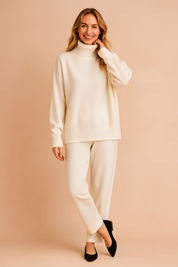 Cream white oversized turtleneck sweater with ribbed cuffs and hem, paired with matching relaxed knit pants and black heeled flats