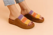 Colorful open-toe wedge sandals featuring three horizontal straps in lavender, orange, and yellow with topstitch details, paired with a textured brown leather base and thick cork platform sole.