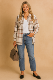 Beige, white, and red plaid button-down overshirt with chest pockets, styled over a white V-neck top and high-waisted blue jeans.