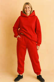 Vibrant red fleece coord set featuring an oversized hoodie with structured shoulders and a roomy hood, paired with high-waisted joggers with a gathered waistband and cuffed hems. Both pieces are made from smooth, heavyweight cotton-blend fabric with a clean, solid finish and no visible prints or embellishments.


