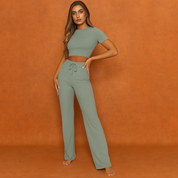 Sage green ribbed loungewear set featuring a fitted crop top with short sleeves and high-waisted drawstring pants with a wide-leg silhouette, made from a soft stretch fabric.