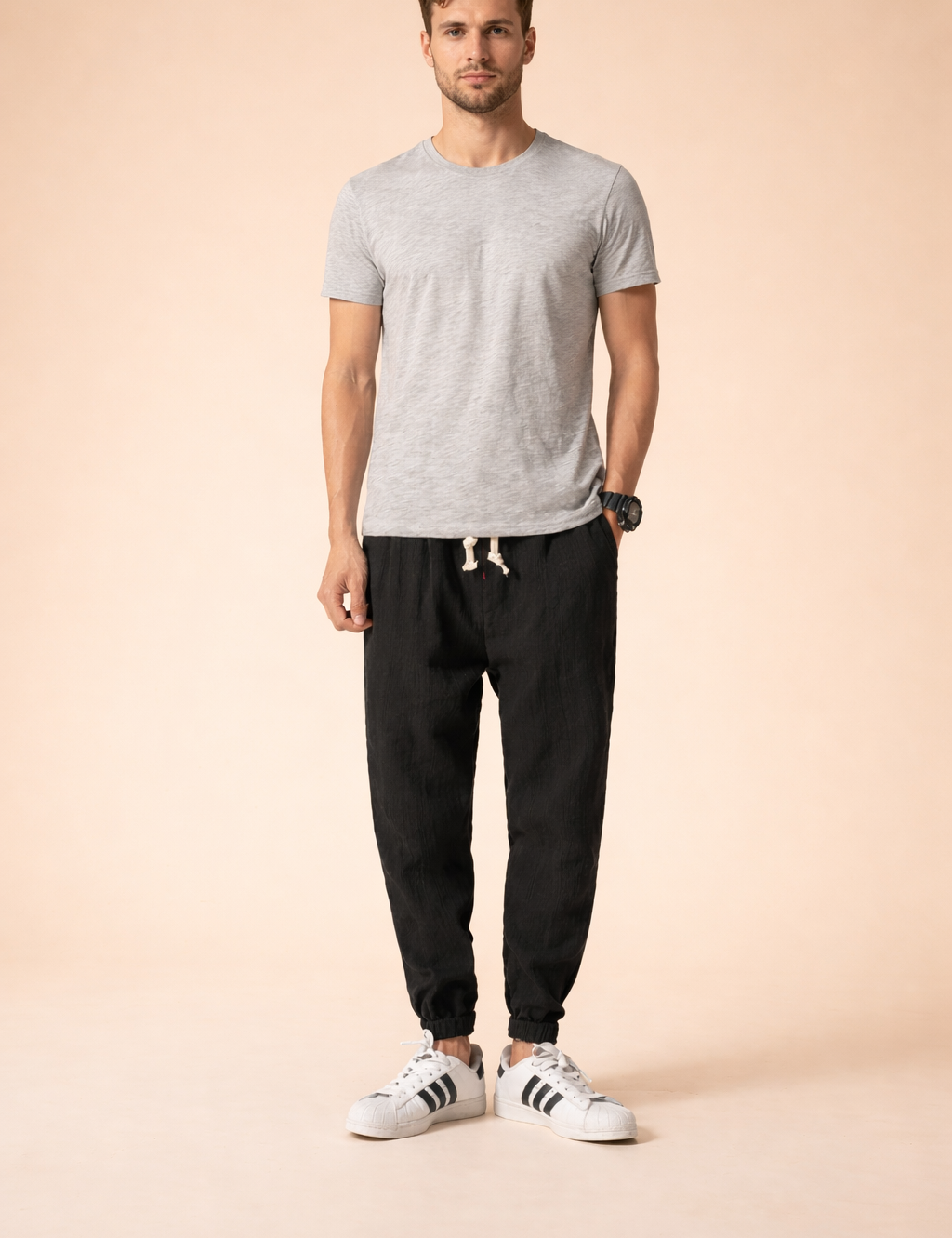 Relaxed-fit black tapered jogger pants with elastic cuffs and adjustable drawstring waist, styled with a minimalist short-sleeve top and clean low-profile sneakers for a modern everyday look.