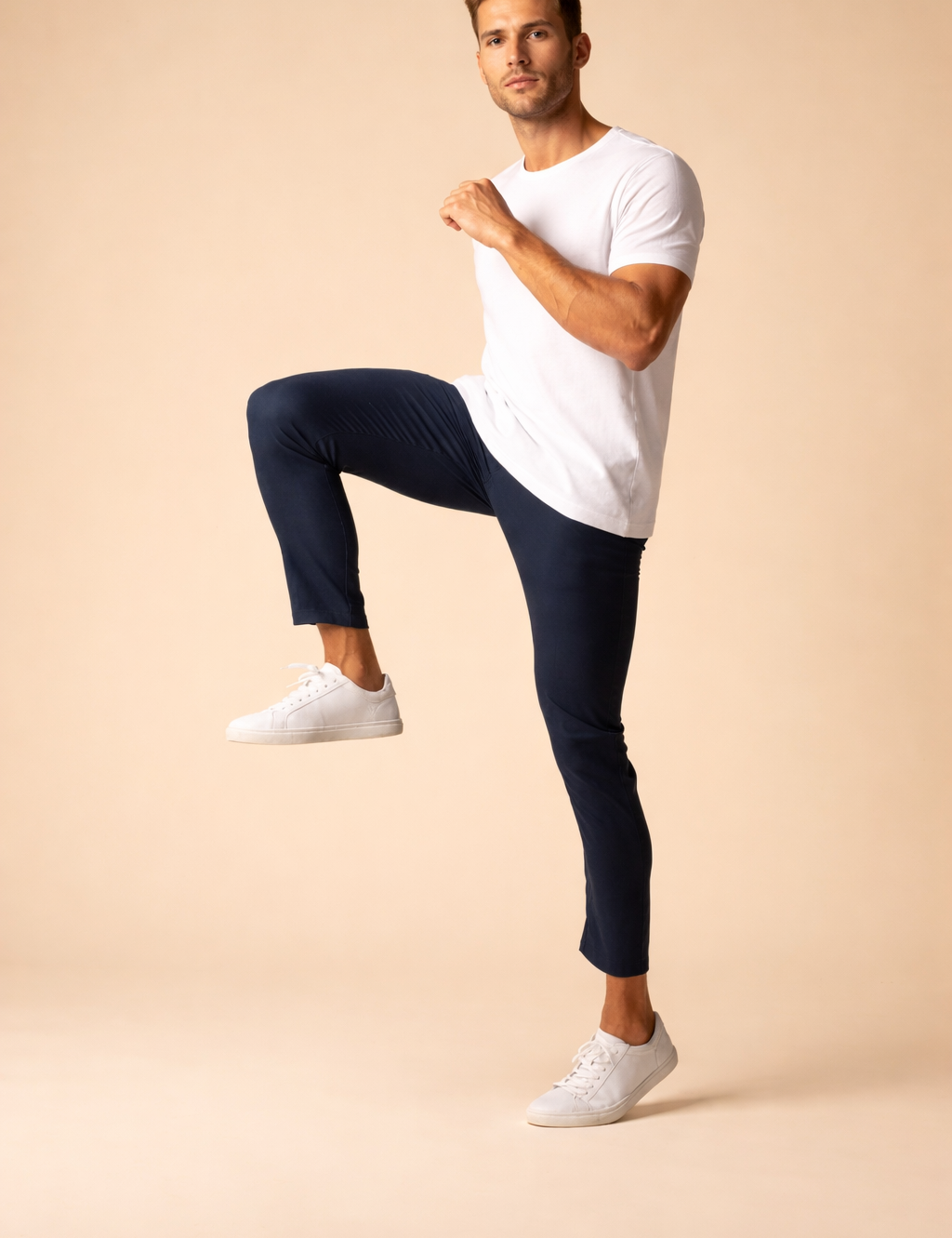 Slim-fit navy blue tapered pants with a clean ankle-length cut, paired with minimalist white low-top sneakers for a modern, streamlined look.