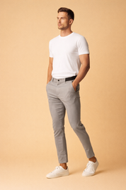 Slim-fit tailored grey trousers with a clean front closure, tapered leg, ankle-length cut, and minimalist silhouette paired with a plain white fitted top and low-profile white sneakers.