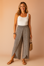 High-waisted tulip-hem wide-leg printed pants in a micro-paisley pattern, styled with a tucked-in white tank top and tan strappy sandals, perfect for chic summer wear.