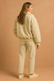 Full-body back view of oversized cream bomber jacket with faux-fur collar, ribbed hem, sleeve pocket, paired with straight-leg pants and cream sneakers.