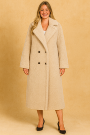 Beige oversized teddy coat with double-breasted button closure, styled with a white top and black heels.