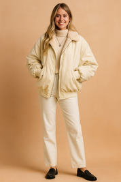 Oversized cream bomber jacket with faux-fur lining, full front zipper, ribbed cuffs and hem, paired with a beige turtleneck and straight-leg pants.