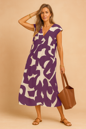 Chic European woman in a purple and beige graphic print midi dress with V-neckline.