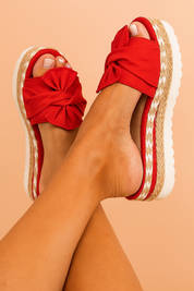 Red espadrille platform sandals with oversized front fabric bows, jute-wrapped midsoles with zigzag stitching, and white ridged rubber outsoles.