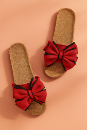 Red bow slide sandals with woven jute soles and black-trim accents on the bows, designed for a casual yet bold summer look.