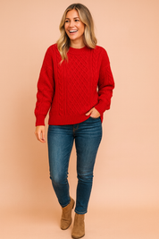 Bright red cable-knit sweater with crew neckline and ribbed cuffs and hem, paired with medium-wash skinny jeans and taupe ankle boots.