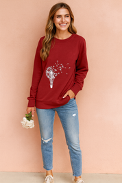 Red long-sleeve sweatshirt with white dandelion and hot air balloon graphic, paired with fitted blue jeans and beige sneakers.