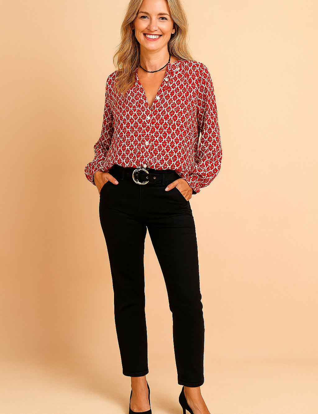 Long-sleeve red blouse with a white geometric pattern, featuring a button-down front and relaxed fit, paired with high-waisted black pants and a black belt with a round metallic buckle.