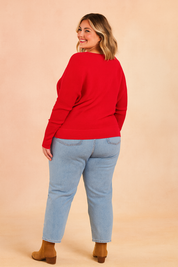 Vibrant red ribbed sweater paired with light blue straight-leg jeans and tan suede ankle boots.