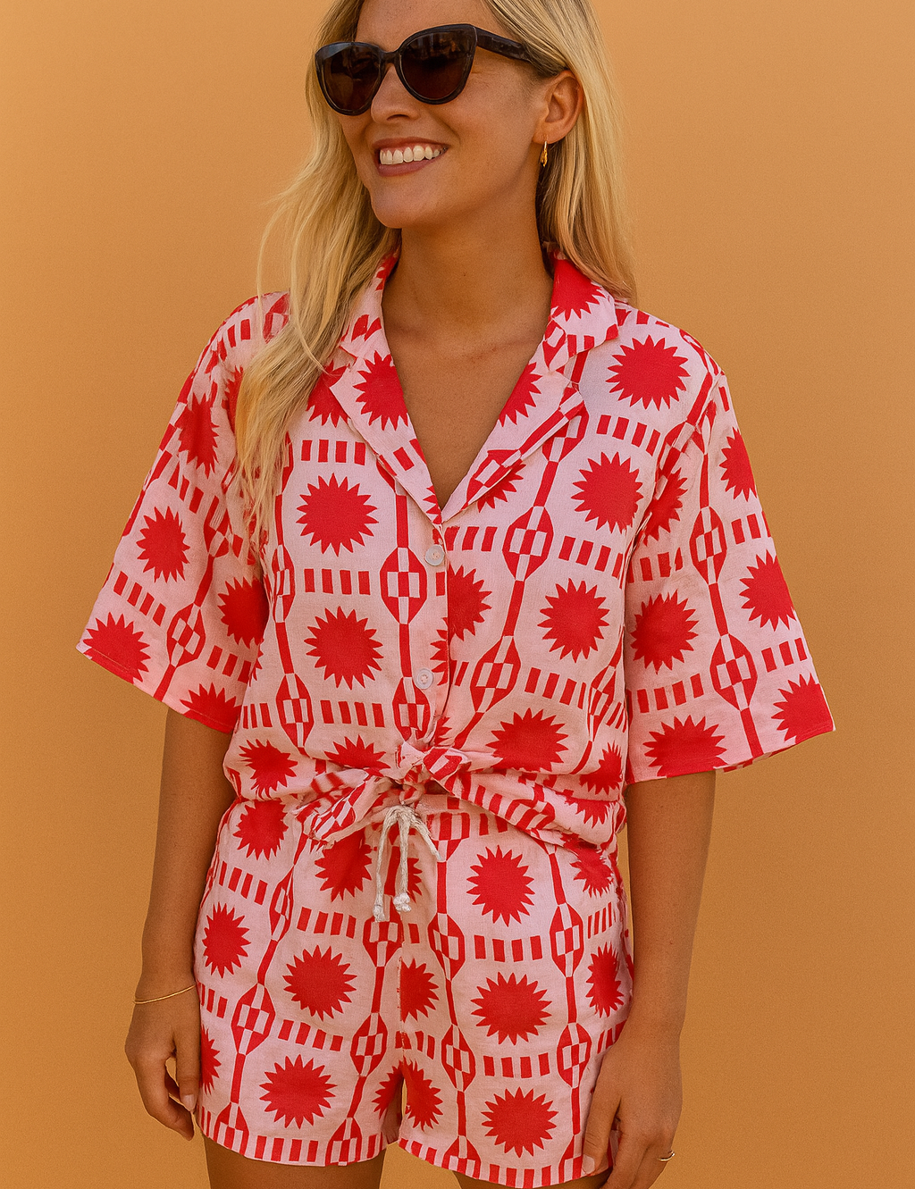 Playful co-ord set featuring a button-up shirt and drawstring shorts with a vibrant red and white geometric sunburst pattern.