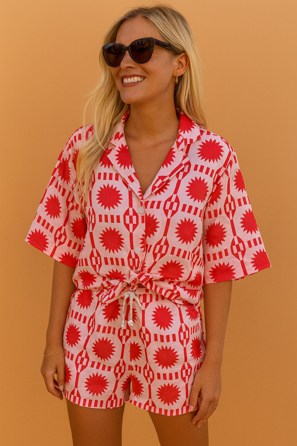 Playful co-ord set featuring a button-up shirt and drawstring shorts with a vibrant red and white geometric sunburst pattern.