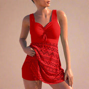 Stylish red swim dress featuring a ruched bust, wide shoulder straps, and a flattering waistband tie detail. The skirt is adorned with intricate geometric laser-cut patterns in matching red tones, creating a vibrant and eye-catching summer look.