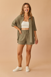 Two-piece coord set featuring a relaxed amry-green button-up shirt with six buttons and a chest pocket, paired with matching drawstring shorts in the same shade and texture, showcasing a casual yet refined cut with visible pocket seams.
