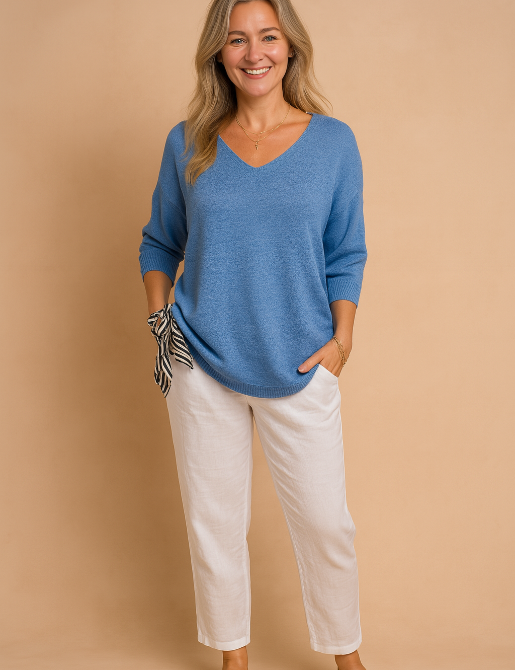 Women's lightweight blue V-neck knit sweater with three-quarter sleeves, paired with white linen trousers and a black-and-white striped scarf detail.
