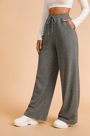 Wide-leg heather gray sweatpants with a drawstring waist and side pockets, styled with a white long-sleeve crop top and chunky white sneakers.