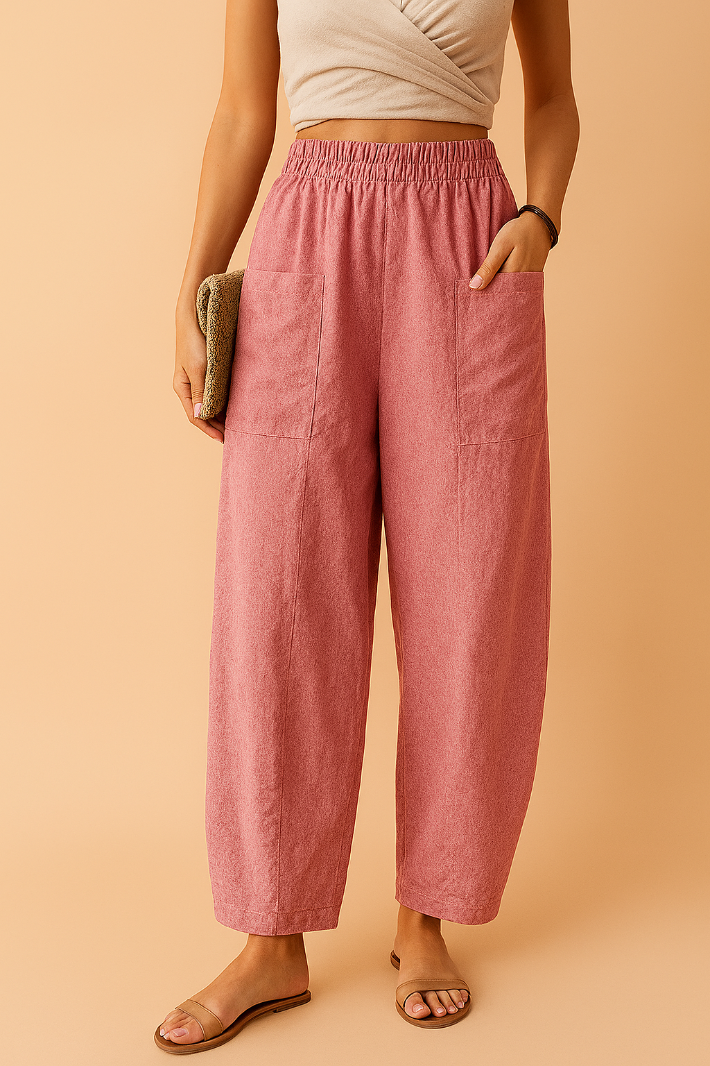 High-waisted wide-leg pink cotton pants with large front patch pockets, soft textured weave, and a relaxed drape, styled with flat sandals and a neutral wrap crop top.