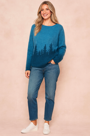 Soft blue fuzzy knit sweater featuring a black evergreen tree silhouette design along the hemline, paired with mid-wash straight-leg jeans and white lace-up sneakers.