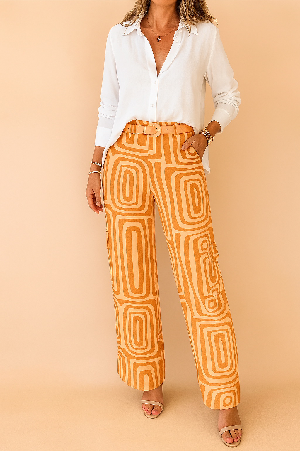 High-waisted orange wide-leg pants with a retro geometric pattern and matching fabric belt, styled with a relaxed white button-up blouse and open-toe nude sandals for a chic modern look