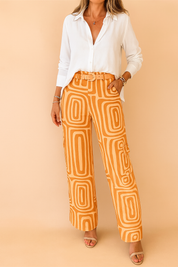 High-waisted orange wide-leg pants with a retro geometric pattern and matching fabric belt, styled with a relaxed white button-up blouse and open-toe nude sandals for a chic modern look