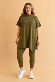 Two-piece ribbed knit co-ord set featuring an oversized short-sleeve tunic and matching fitted leggings in deep olive green, styled with side slits and a high neckline for casual comfort.