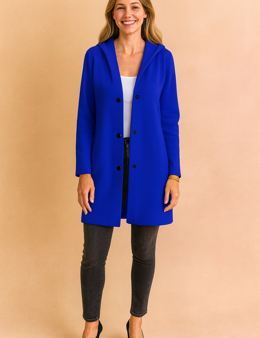 Royal blue hooded longline coat with black button closure, styled over a white top and paired with dark skinny jeans and black heels for a chic modern look.