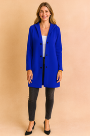 Royal blue hooded longline coat with black button closure, styled over a white top and paired with dark skinny jeans and black heels for a chic modern look.
