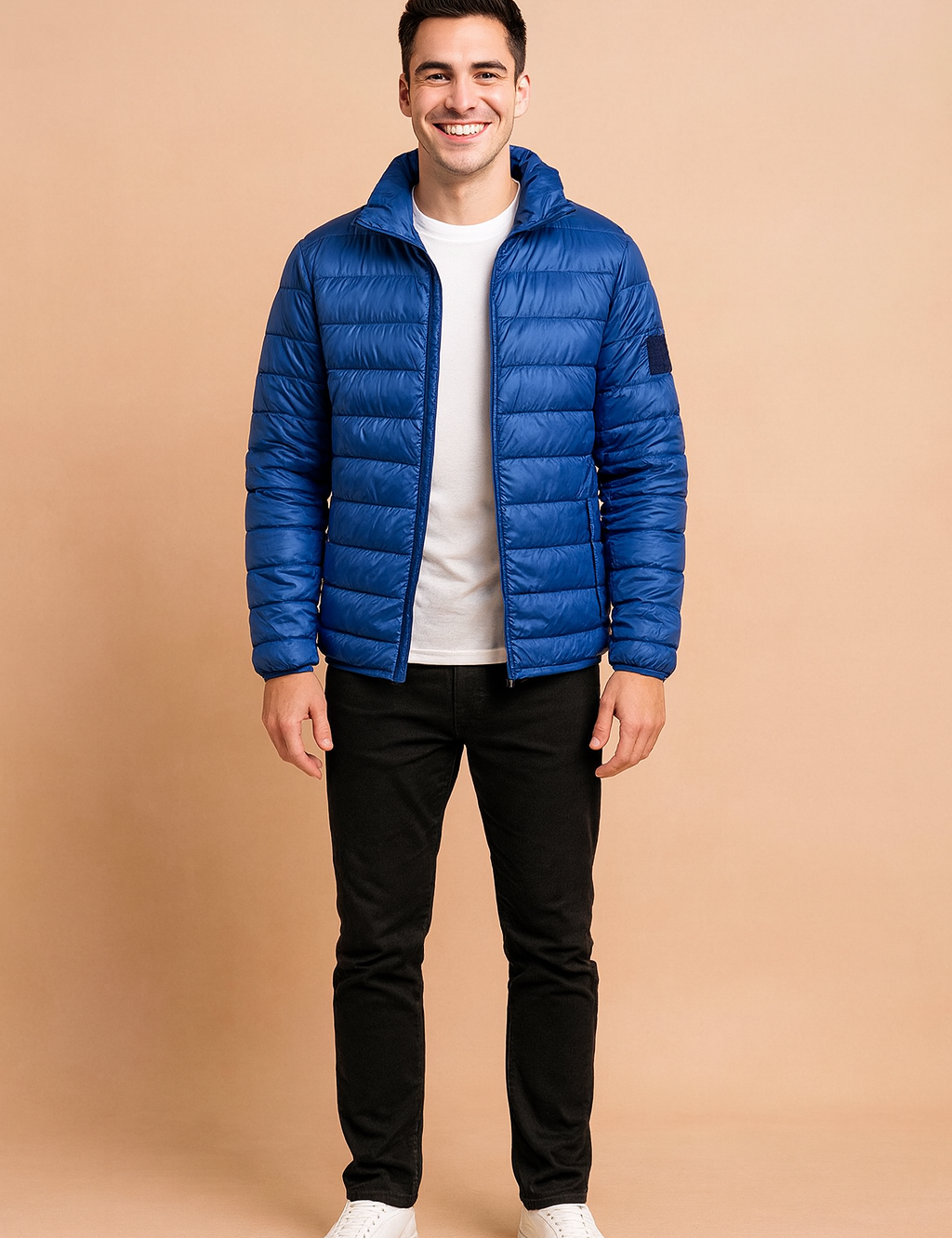 Royal blue puffer jacket with horizontal quilted design and front zipper, styled with a white t-shirt, black trousers, and white sneakers.