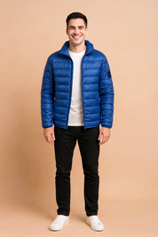 Royal blue puffer jacket with horizontal quilted design and front zipper, styled with a white t-shirt, black trousers, and white sneakers.
