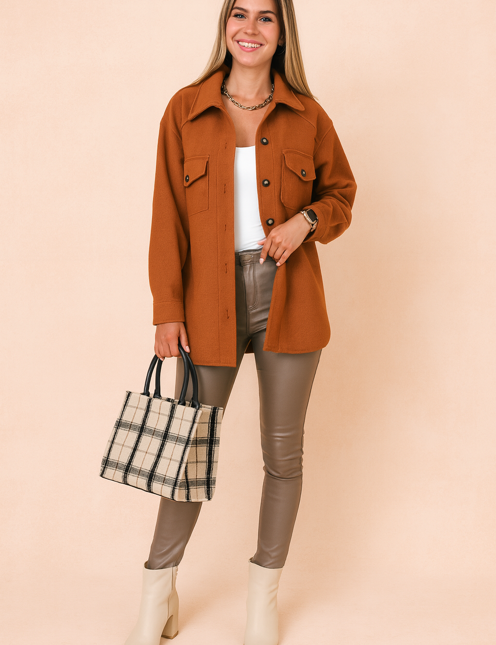 Rust brown button-up wool jacket with flap pockets, styled over a white fitted tank top, taupe slim-fit leather pants, plaid tote bag, and cream ankle boots for a modern chic look.