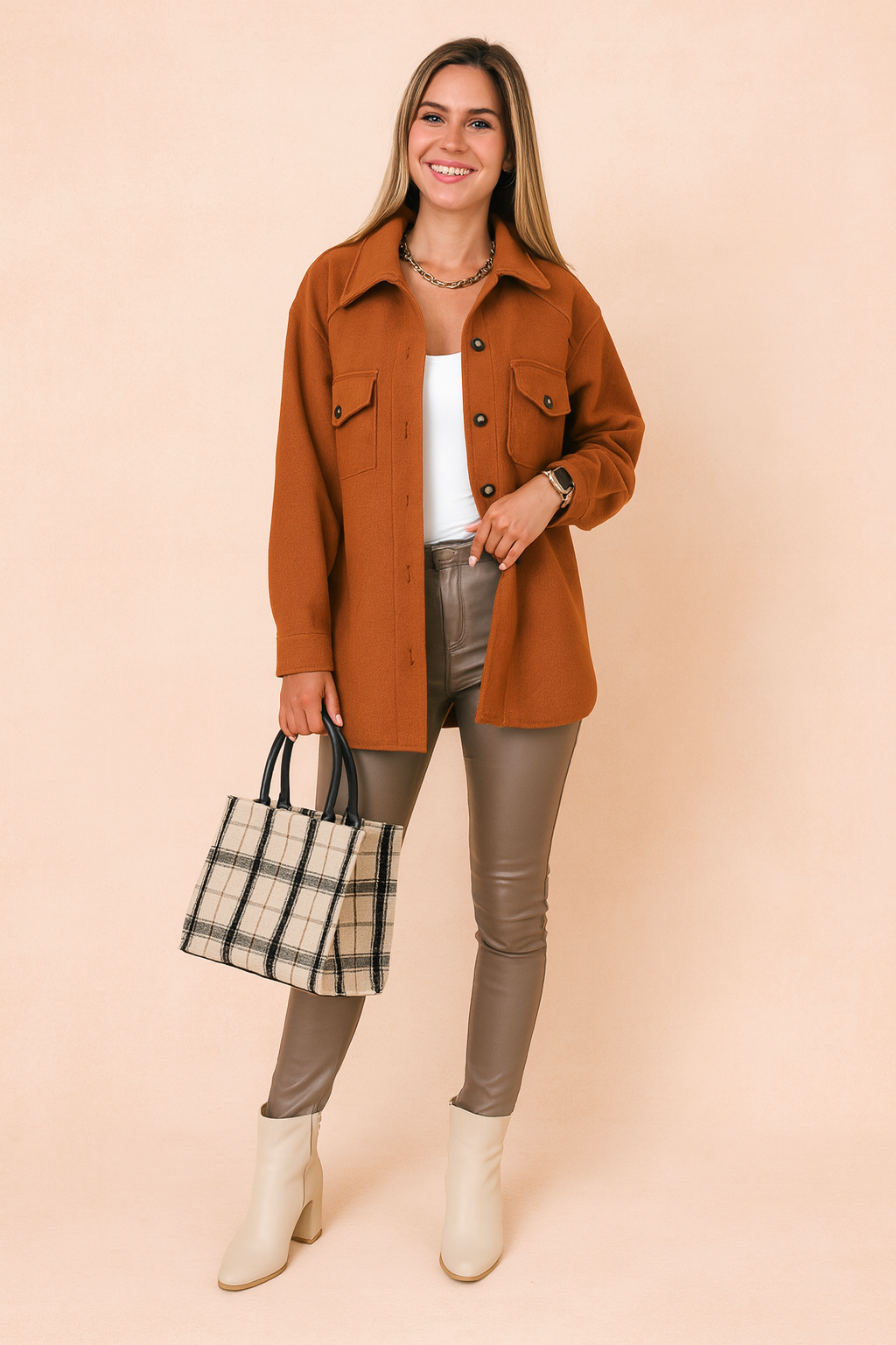 Rust brown button-up wool jacket with flap pockets, styled over a white fitted tank top, taupe slim-fit leather pants, plaid tote bag, and cream ankle boots for a modern chic look.