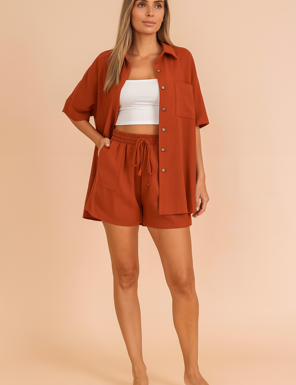 Rust orange button-down shirt and shorts co-ord set for women, featuring a relaxed fit and lightweight fabric, styled over a white crop top in a pastel blush fashion studio background.