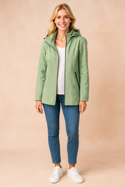 Women's sage green hooded parka jacket with subtle botanical print, front zipper closure, and zippered side pockets, styled with a white T-shirt, slim blue jeans, and white sneakers