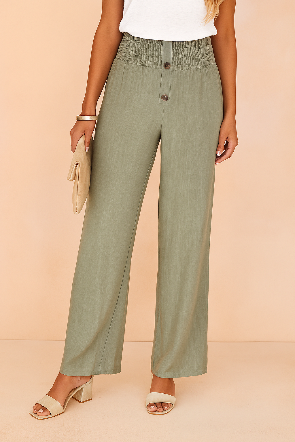 High-waisted sage green wide-leg pants with smocked waistband and two-button closure, styled with beige block-heeled sandals and a neutral clutch for an effortlessly chic look.