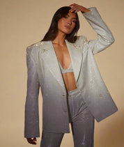 Three-piece shimmering silver co-ord set featuring a structured oversized blazer with subtle shoulder padding and two-button closure, a matching glitter-finish bralette top, and high-waisted fitted trousers with a metallic texture throughout.