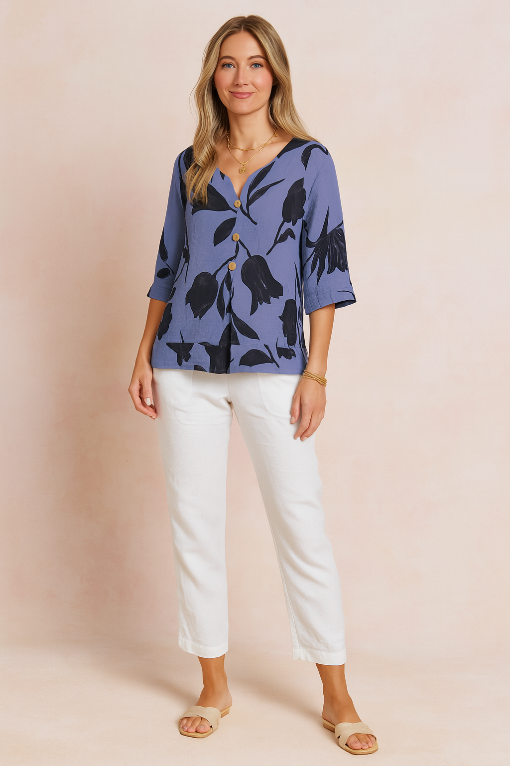 Button-front slate blue blouse with large black tulip floral print, featuring a relaxed fit, V-neckline, and three-quarter sleeves, styled with white linen trousers.