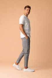 Slim-fit grey tailored trousers with a clean tapered leg, ankle-length cut, minimalist side pockets, smooth structured finish, and a refined modern silhouette paired with low-profile white sneakers.