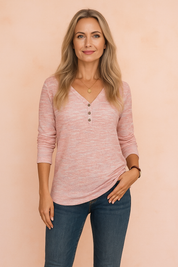 A soft pink textured long-sleeve Henley top with button detail, styled with fitted denim jeans