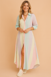 Long-sleeve button-down striped maxi shirt dress in vertical pastel tones of mint, lavender, blush pink, and butter yellow, featuring a high side slit and casual rolled cuffs, styled with white low-top sneakers.