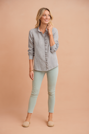 Vertical striped button-up blouse in light grey and white with ruffle trim along the placket and cuffed long sleeves, paired with mint green skinny ankle jeans and beige espadrille flats.