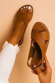  Women's flat brown crisscross strap sandals with a rounded open toe and contrast white stitching, crafted in smooth leather.