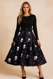 Sukienka halloweenowa retro z czarną górą z długim rękawem, satynową kokardą w talii i rozkloszowaną spódnicą ozdobioną nadrukiem białych czaszek z fioletowymi różami i nietoperzami.